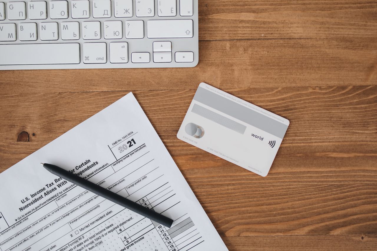 home-hero-bg Overhead view of a desk with tax form, pen, keyboard, and contactless card.